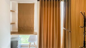 A room with a window, a chair, a desk, and a coat rack. - Relaxing And Cozy Studio Tokyo Riverside Pik 2 Apartment (Teluknaga)