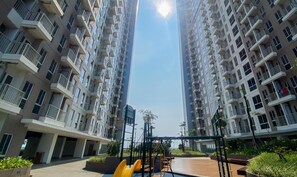 Un edificio residencial alto con varios balcones, un patio central con equipo de ejercicio y una vista despejada del cielo.