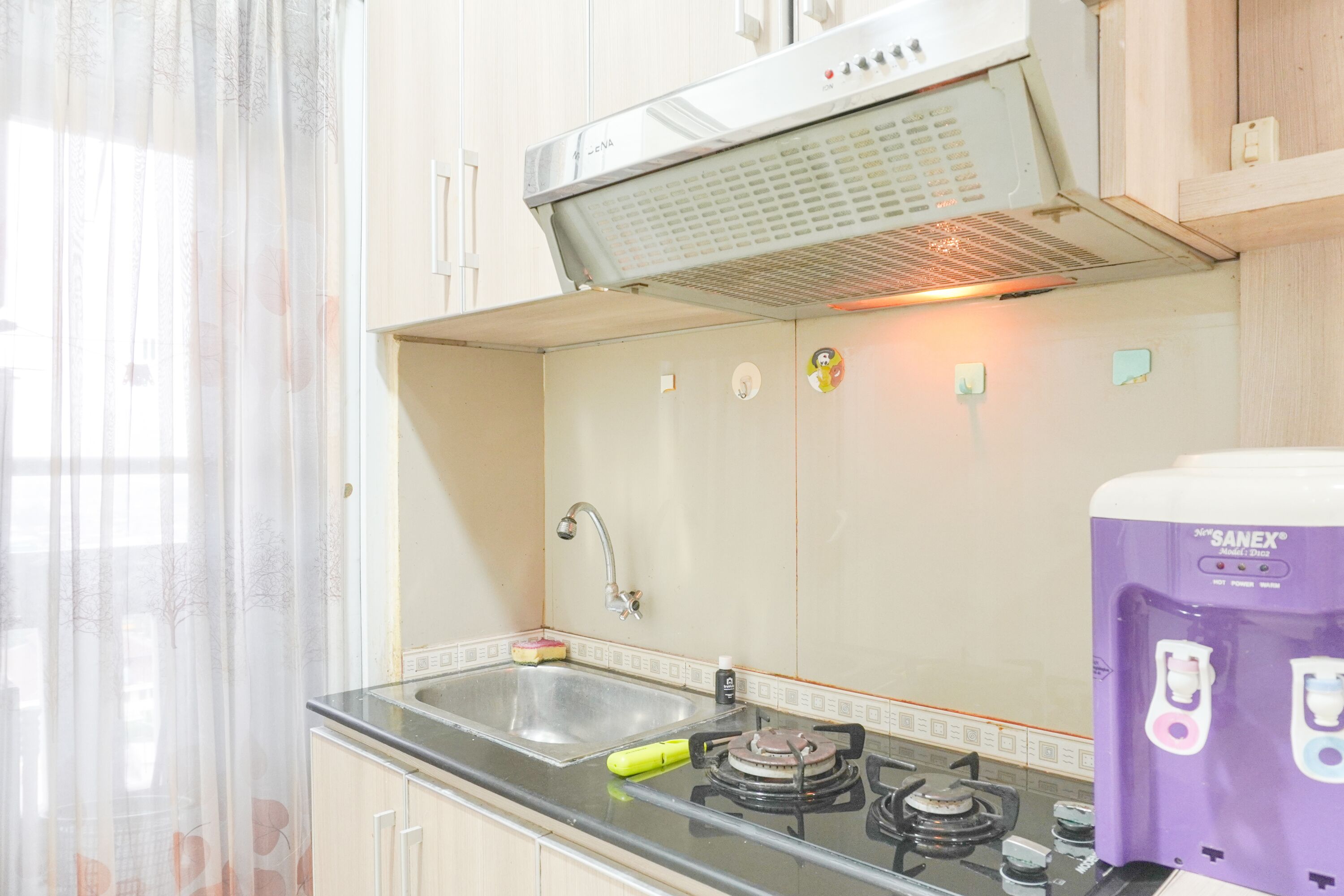 Une cuisine équipée d’une cuisinière à gaz, d’un évier et d’une hotte aspirante en acier inoxydable.