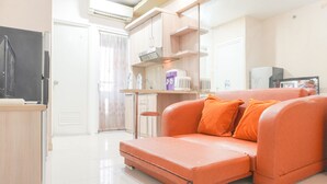 Un espace de vie compact comprenant un canapé, une kitchenette et un petit coin repas.