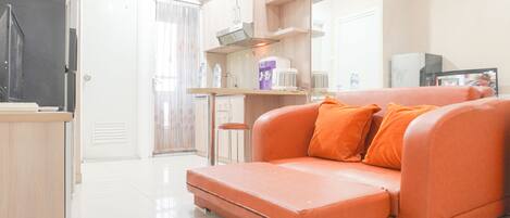 A compact living space with a sofa, kitchenette, and a small dining area.