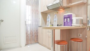 Une cuisine compacte dotée d’une cuisinière intégrée, d’un distributeur d’eau et de deux tabourets.