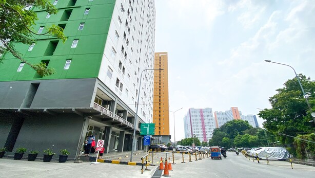 Un immeuble à plusieurs étages, doté d’une façade verdoyante et d’un panneau indiquant un espace de stationnement.