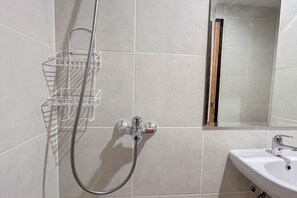 A bathroom with a shower, a sink, and a mirror.