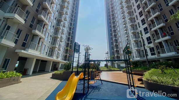Um edifício residencial com parquinho infantil, incluindo um escorrega amarelo e balanços.