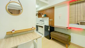 Uma cozinha compacta com bancada de madeira, uma geladeira pequena e um banco.
