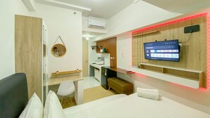 Quarto de hotel moderno com uma cama, uma mesa, uma cadeira, uma TV e uma pequena copa.