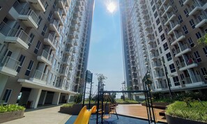 A residential building with a playground featuring a yellow slide and swings. - Modern Look Studio Apartment At Tokyo Riverside Pik 2 (Teluknaga)