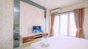 Une chambre d’hôtel avec un lit, une télévision, un bureau et une fenêtre avec des rideaux.