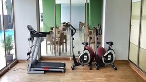 A gym with a treadmill, stationary bikes, and a mirrored wall. - Cozy 2Br Apartment Mekarwangi Square Cibaduyut (Bandung)
