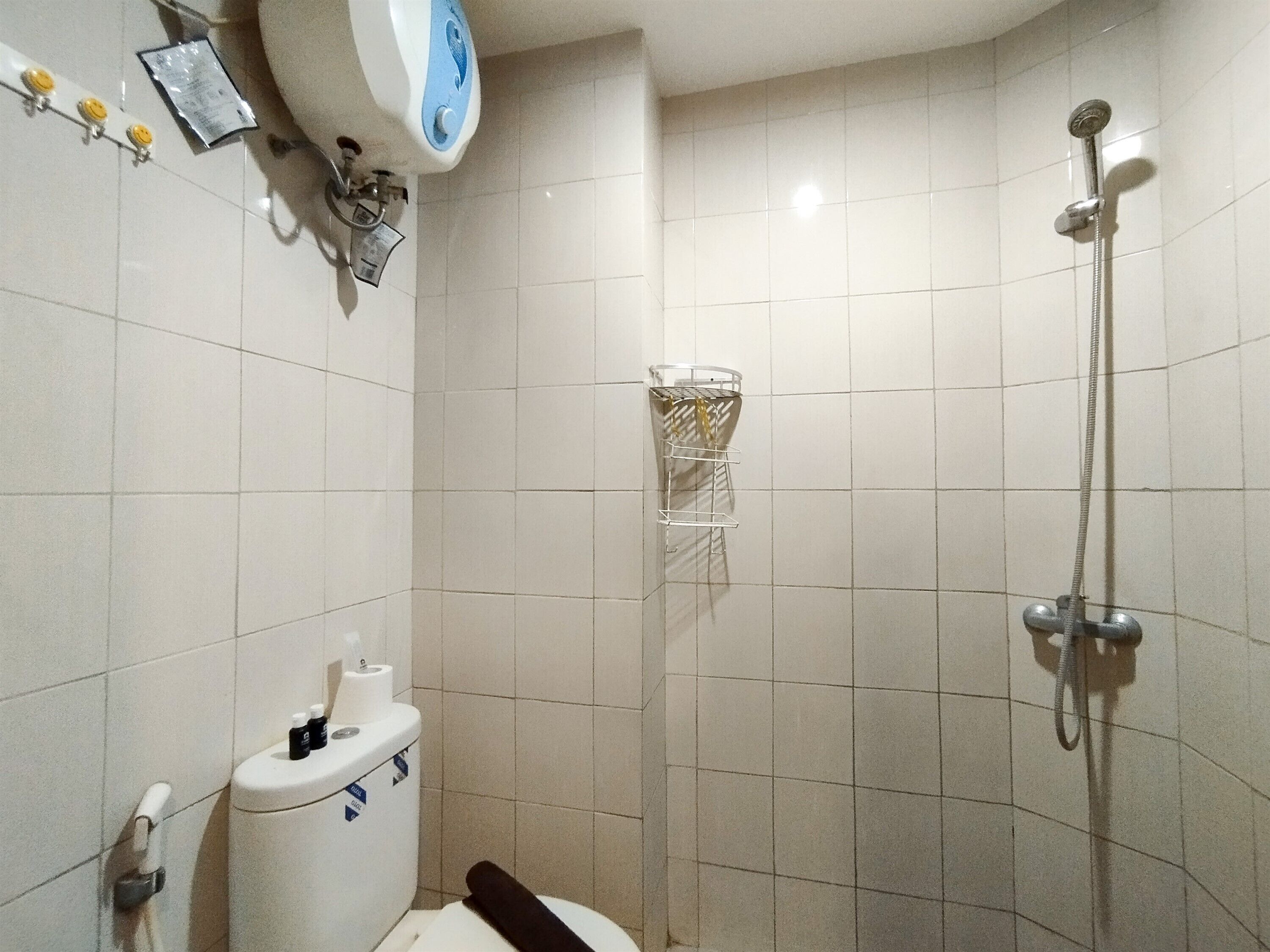 A small bathroom with a toilet, a shower, and a towel rack.
