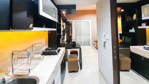 A modern kitchen with a central island, built-in appliances, and a sliding glass door leading to a dining area. - Brand New And Good Simply 1Br At Uttara The Icon Apartment (Depok)