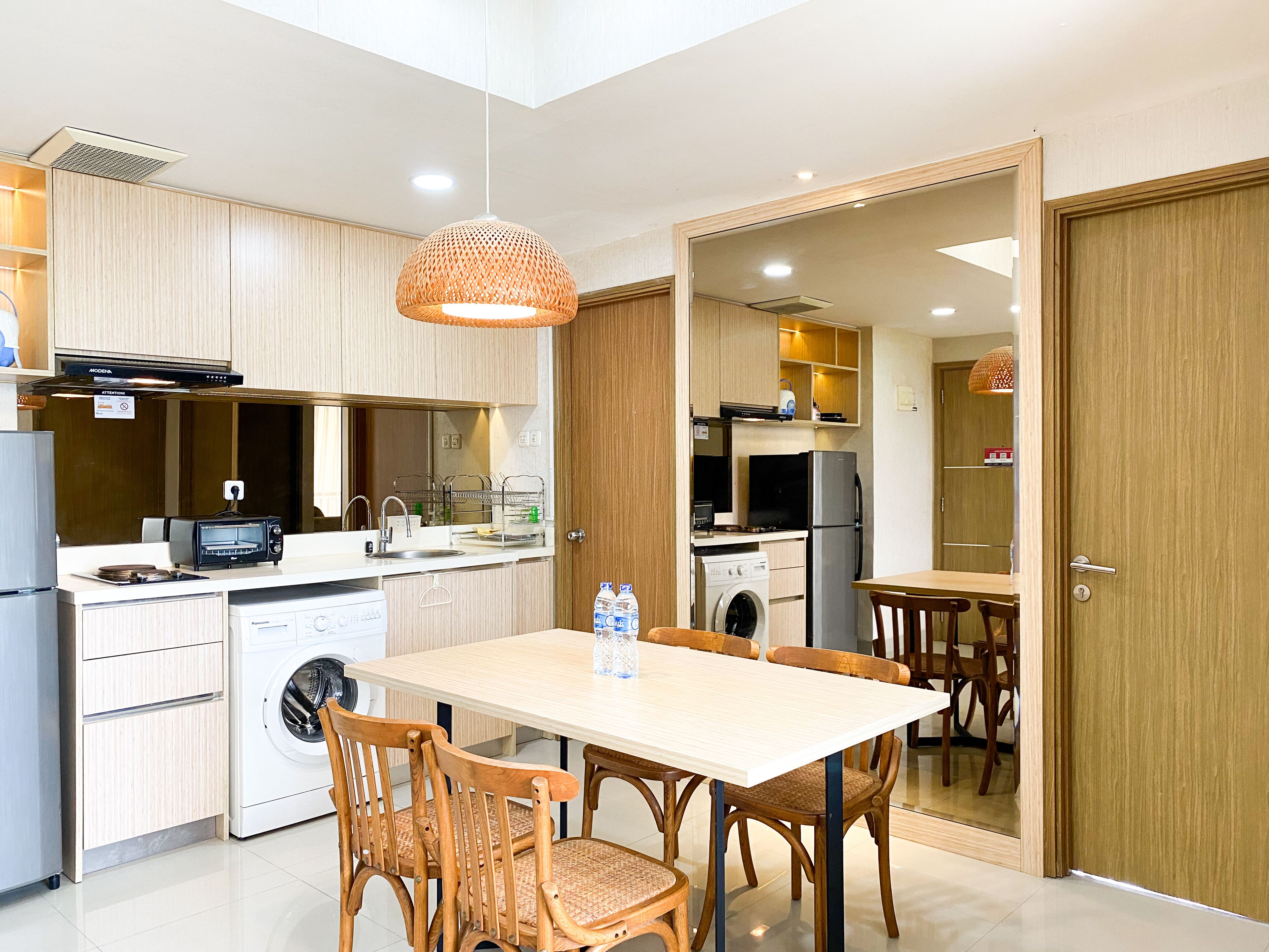 A compact kitchen with a dining area, including a washing machine, a refrigerator, and a microwave.