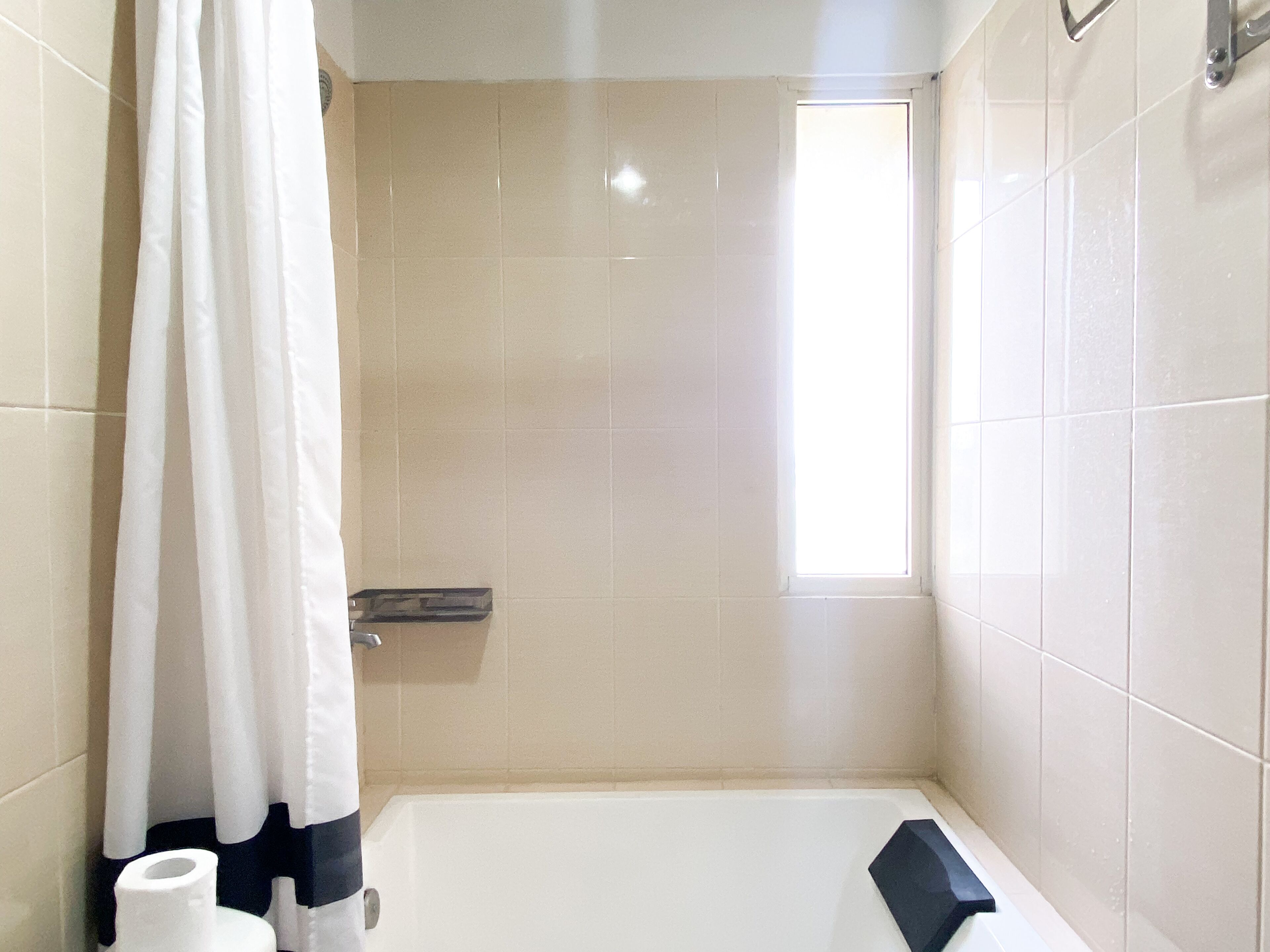 Ein Badezimmer mit einer Badewanne, einer Duschvorhang und einem Fenster.