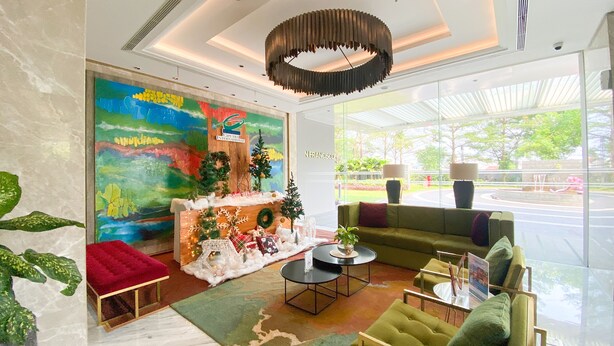 A modern lobby with a colorful mural, a Christmas tree, and a green sofa. - Well Designed And Strategic 2Br At Ciputra International Apartment (Jakarta)