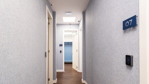 Un pasillo con un letrero con el número '07' en la pared, una puerta con cerradura electrónica y un accesorio de iluminación en el techo.