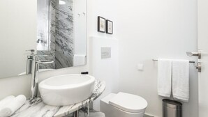 Un baño moderno con lavamanos de mármol, inodoro y ducha.