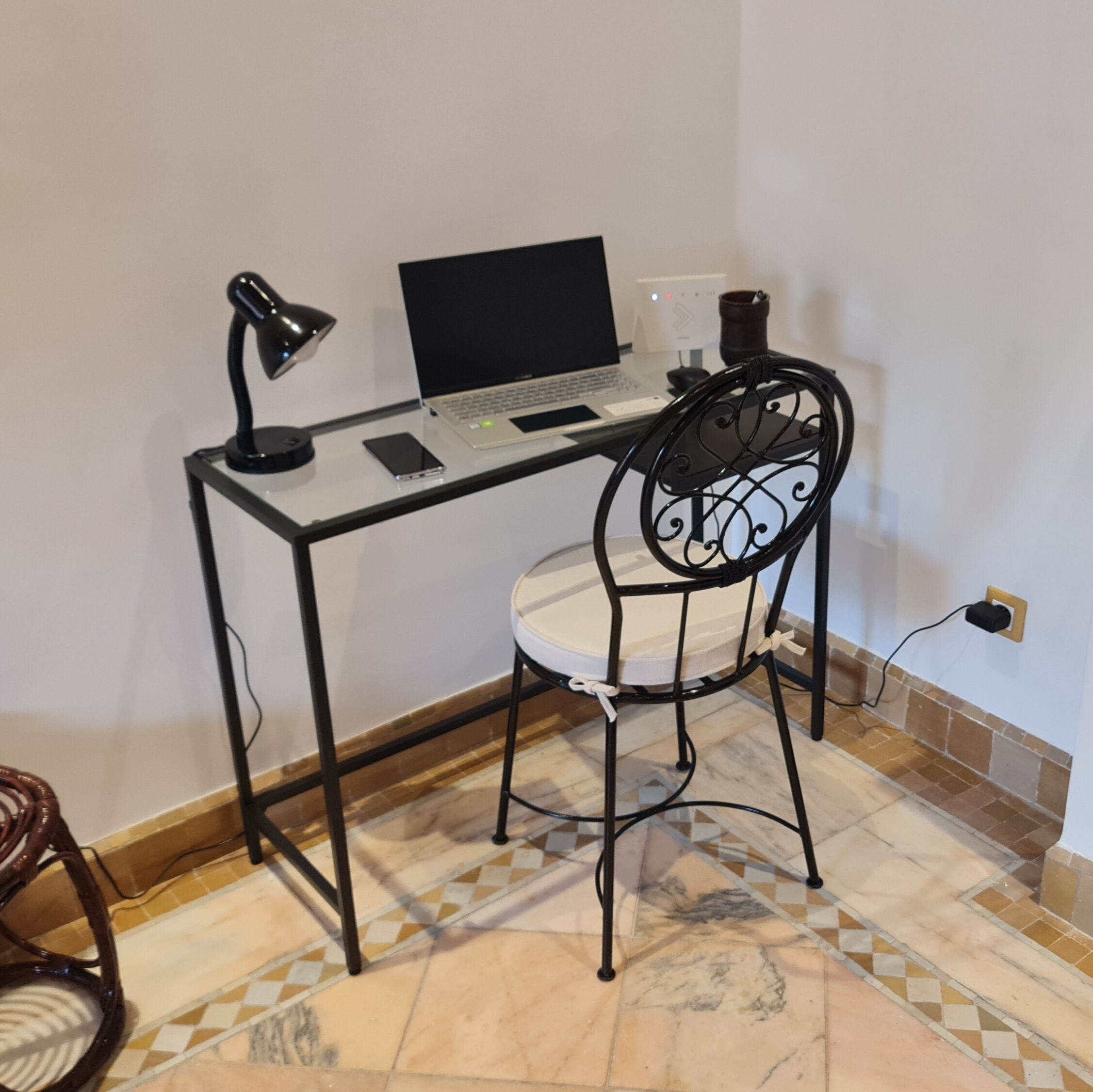 A workspace with a laptop, desk lamp, and chair.