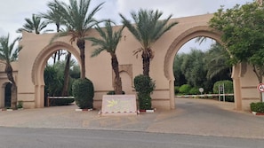A gated entrance with palm trees and a sign indicating a hotel named 'Copaniche Gardens.'