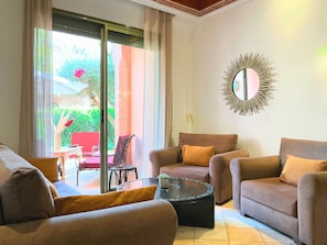 A living room with a sofa set, a coffee table, and a large mirror on the wall.