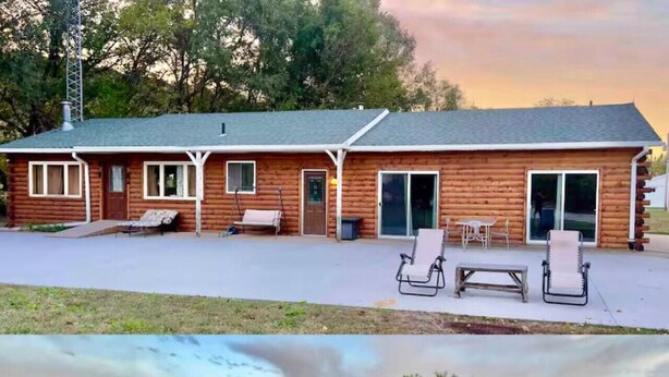 A wooden cabin with a patio area featuring two lounge chairs and a fire pit.