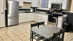 A compact kitchen with white cabinets, a stainless steel refrigerator, a microwave, and a stove.