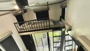 Een moderne loftruimte met een bank, een eettafel en een trap naar een hoger gelegen niveau.