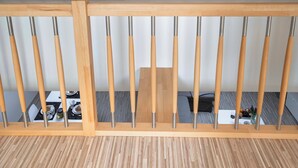 A wooden railing with metal bars, a dining table with chairs, and a small table with a vase and decorative items. - 150m² 4BR Duplex Near Metro & Prague Center (Hlavní mesto Praha)