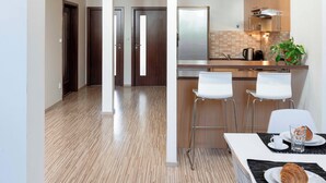 A modern kitchen with a central island, pendant lighting, and a dining area with a table set for two. - 150m² 4BR Duplex Near Metro & Prague Center (Hlavní mesto Praha)