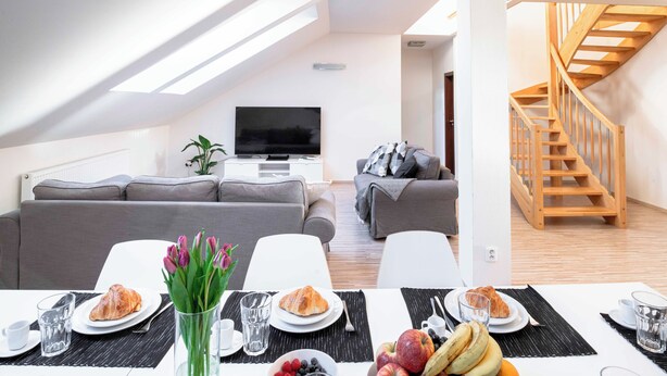 A modern living room with a dining area, a TV, and a staircase. - 150m² 4BR Duplex Near Metro & Prague Center (Hlavní mesto Praha)