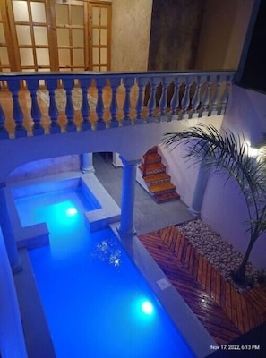 Stunning courtyard with a serene water feature and staircase leading to an upper level, surrounded by a tropical ambiance.