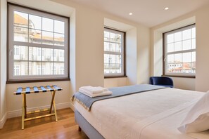 A hotel room with a bed, a chair, a window, and a small table with towels.
