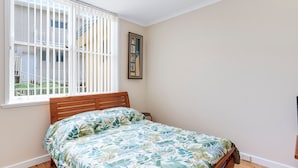 A bedroom with a bed, a window with blinds, a framed picture on the wall, and a staircase visible outside. - Golden-Sands- 3-66-Ocean-Pde (The Entrance)