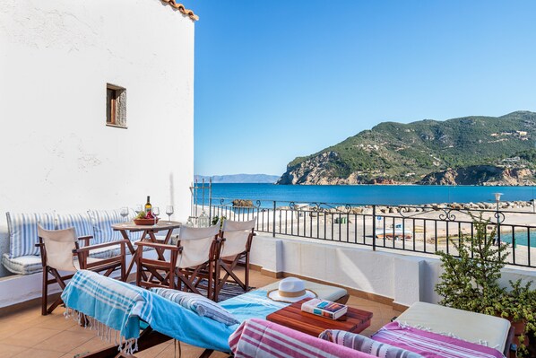 Un balcón con vistas al mar, una mesa de comedor y sillones de descanso.