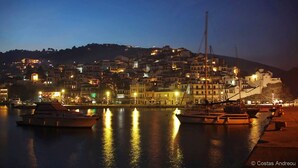 A coastal town at night with buildings along the waterfront and boats docked.
