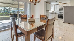 Una cocina moderna con una mesa de comedor de cristal, sillas de madera y una lámpara de araña.