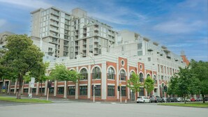 Un edificio residencial de varios pisos con fachadas de ladrillo y vidrio, ventanas grandes y balcones.
