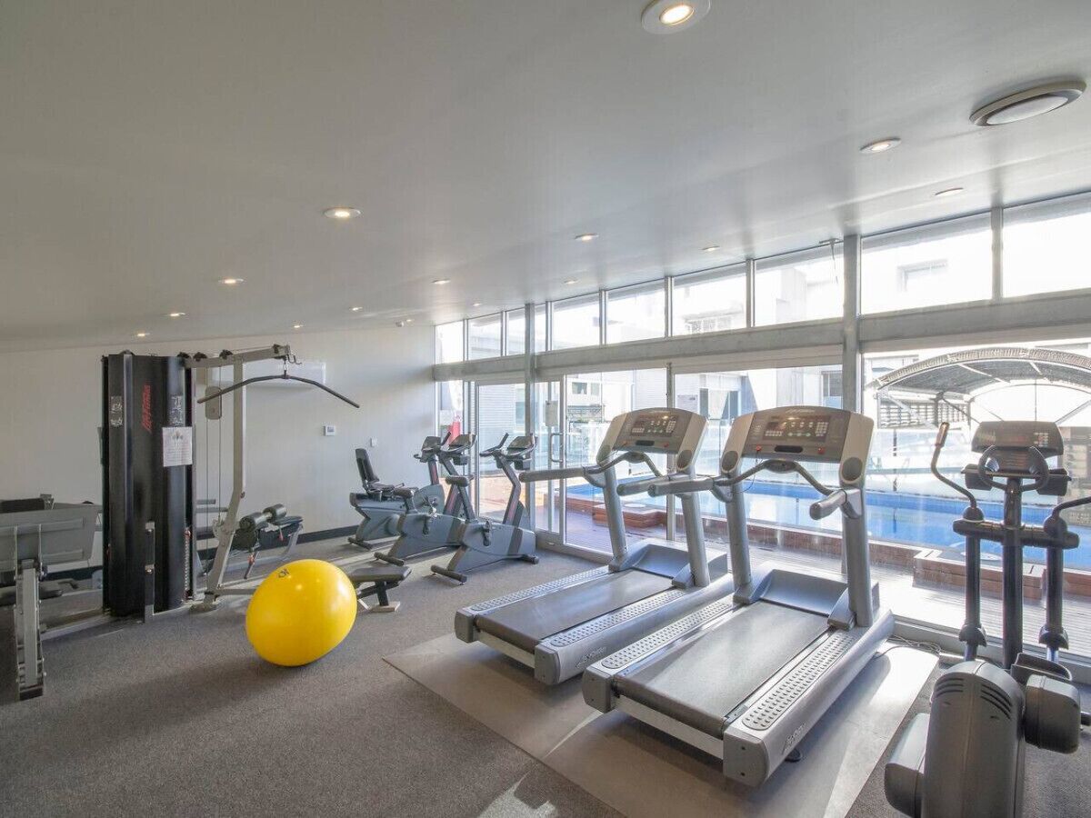 A gym with treadmills, elliptical machines, and a yellow exercise ball.