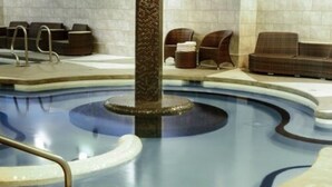 A pool area with a central column, lounge chairs, and a seating area.