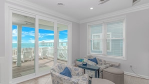 A room with a view of the ocean, a sliding glass door, a seating area with a table, and a window with blinds. - True beachfront home with stunning views, near Surfside Pier and restaurants (Surfside Beach)