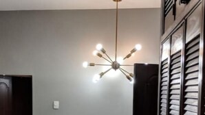 Un couloir agrémenté d’une rampe en métal décorative, d’un luminaire au plafond et d’une porte.