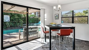 Une cuisine moderne avec un coin repas, de grandes fenêtres et une vue sur une piscine.