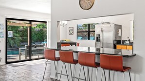 Une cuisine moderne dotée d’un grand îlot central, de tabourets de bar et d’un réfrigérateur.