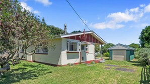 Uma casa térrea com varanda da frente, garagem e um pequeno jardim.