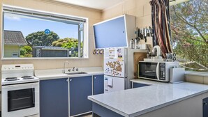 Cozinha compacta com fogão, pia, geladeira e micro-ondas.