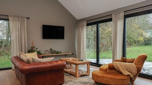 Una sala moderna con un sofá de cuero, una mesa de centro de madera y un ventanal con cortinas.