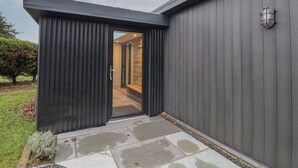 Un bâtiment moderne à l’extérieur sombre, doté d’une entrée pavée de pierres et d’un couloir intérieur visible.