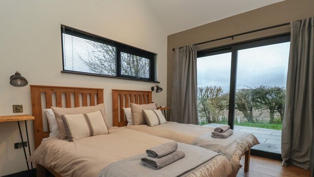 Une chambre double avec deux lits, une grande fenêtre et une vue sur les arbres.