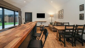 Une cuisine moderne avec un plan de travail en bois, un ventilateur de plafond et un coin repas comprenant une table et des chaises en bois.
