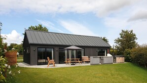Une maison moderne dotée d’un patio, de portes-fenêtres coulissantes et d’un espace barbecue.